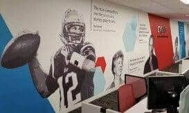 A long wall displays a horizontal timeline showcasing photos and text that highlight key moments and achievements of the New England Patriots organization.
