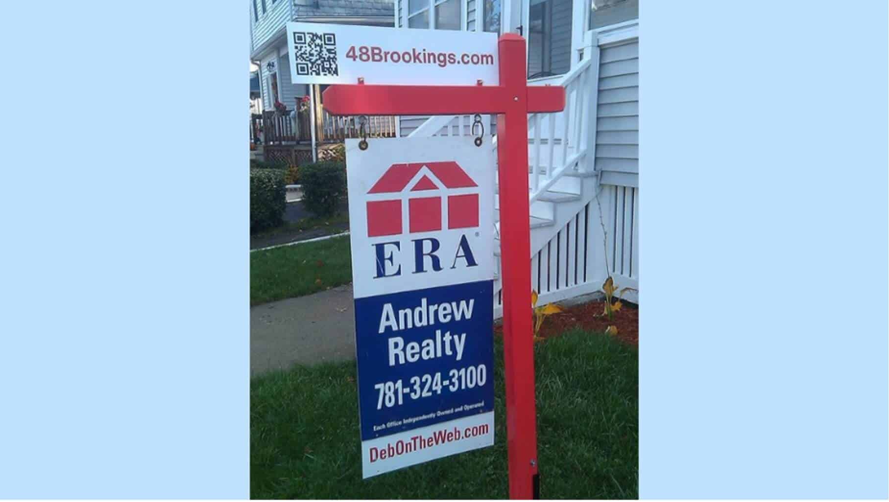 A for sale sign in the front yard of a home. The placard features a QR code that potential buyers can use to get more information about the listing.