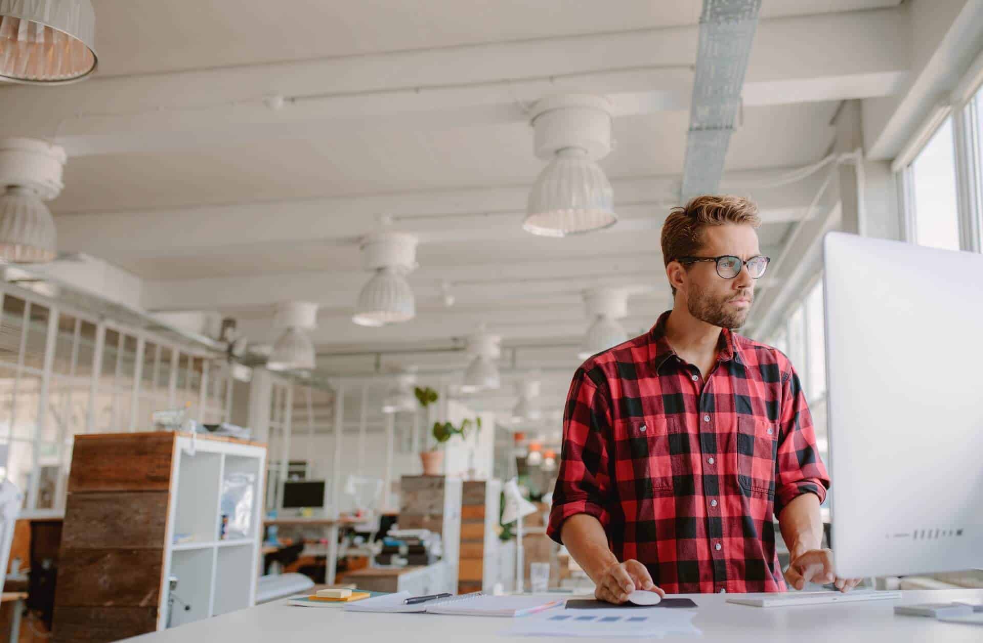 Man standing at desk in open office