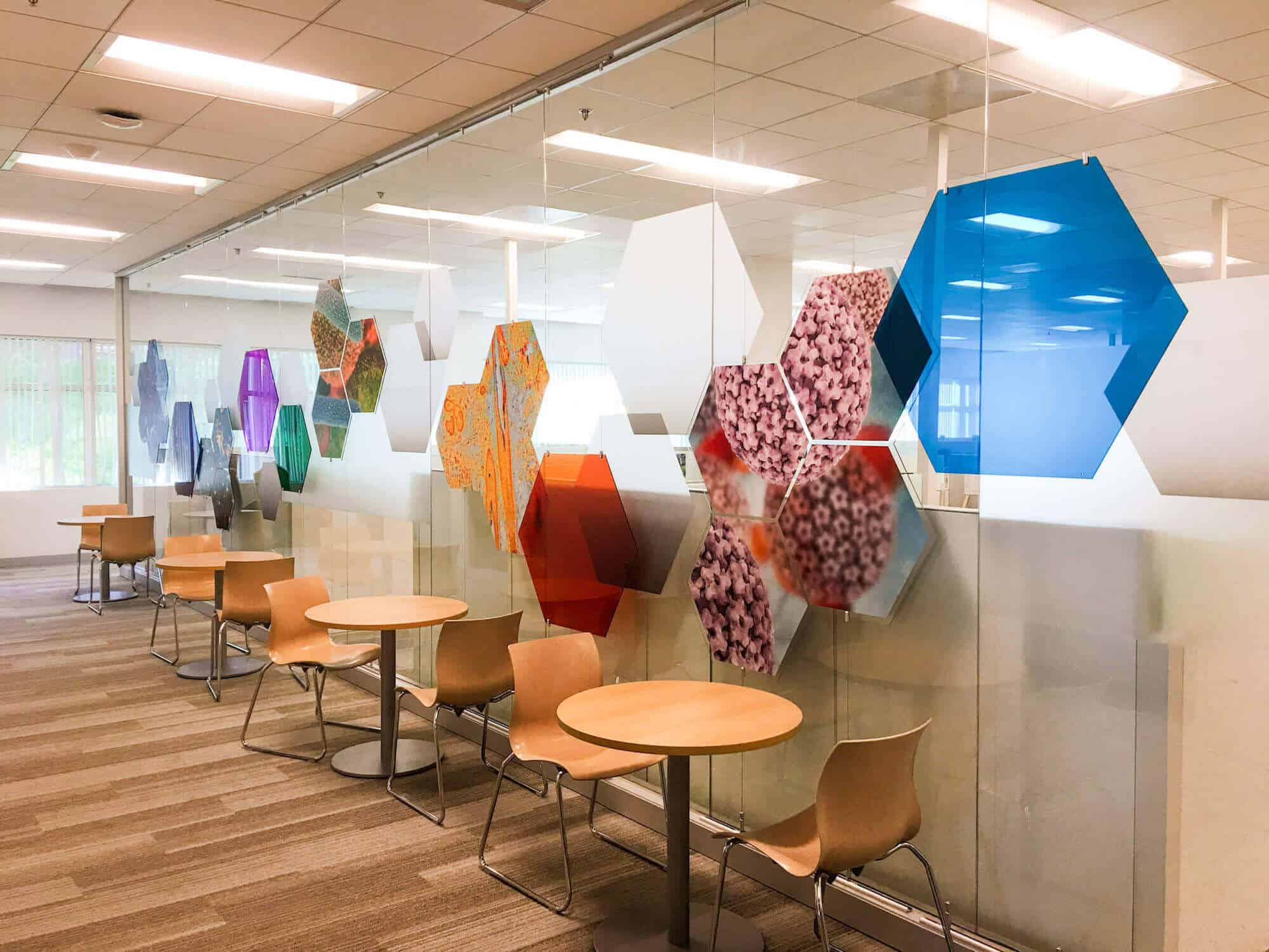 office-window-with-colorful-octagon-design-across-as-a-privacy-wall. wooden-chairs-and-table-line-the-front-of-the-window.