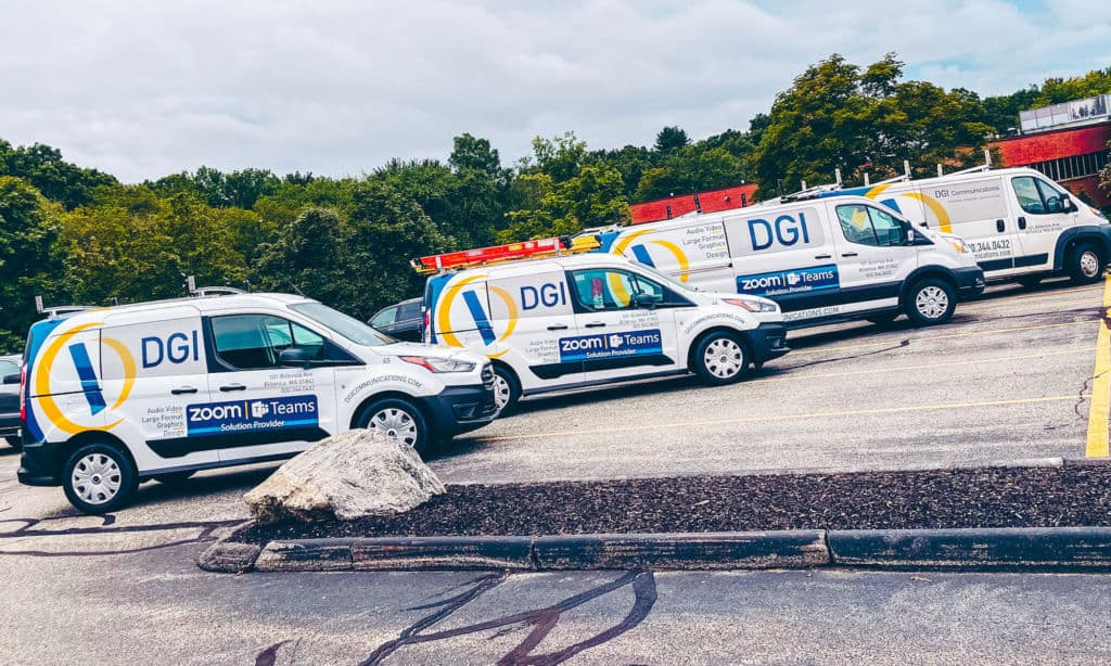 Four mid-sized vans parked next to each other are wrapped with the DGI logo and contact information.