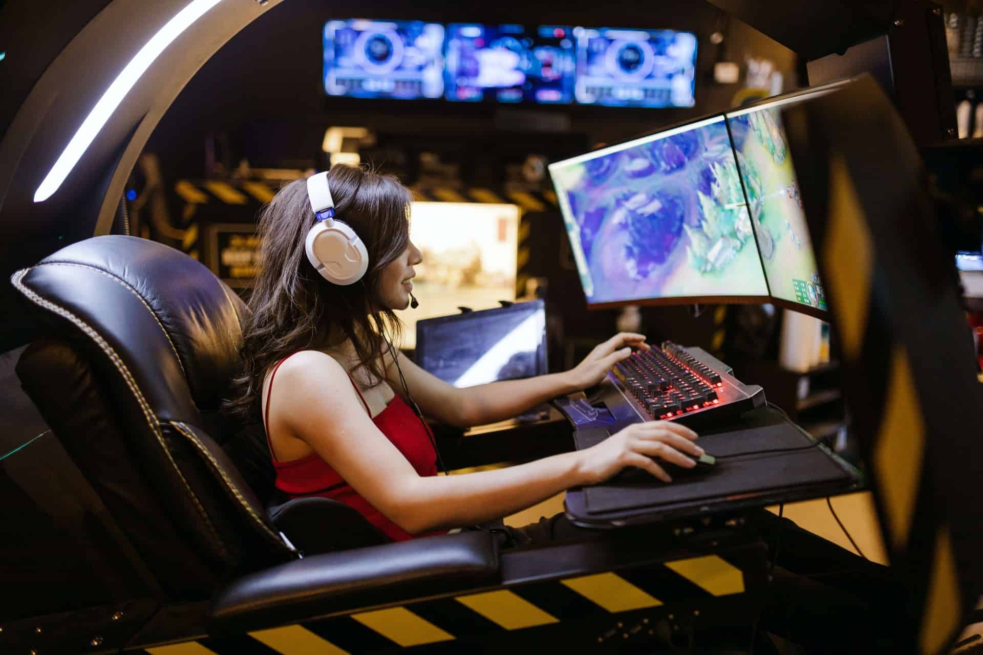 Woman wearing a headset playing a video game on a panoramic computer monitor