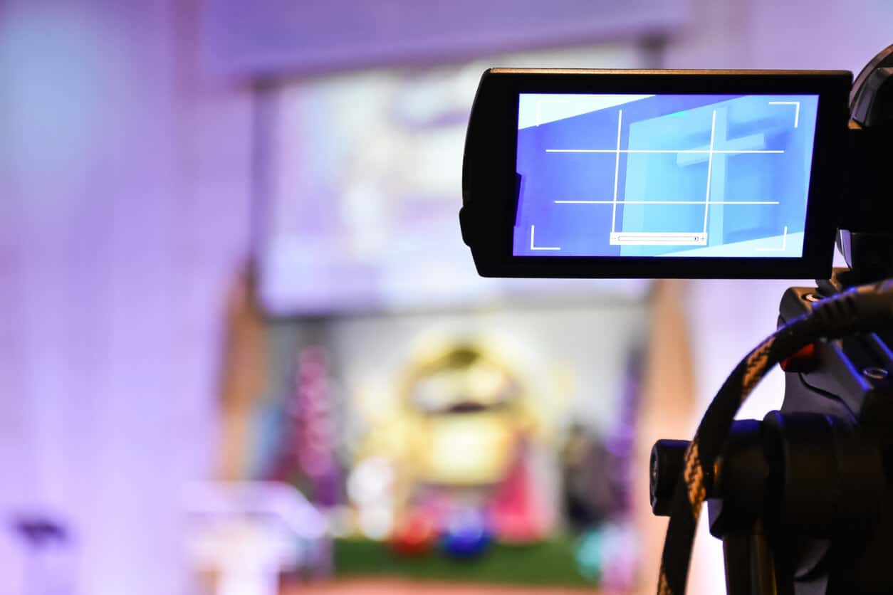 Close-up of a camcorder that's set up in front of an altar to film a church service. The display screen shows an image of a cross.